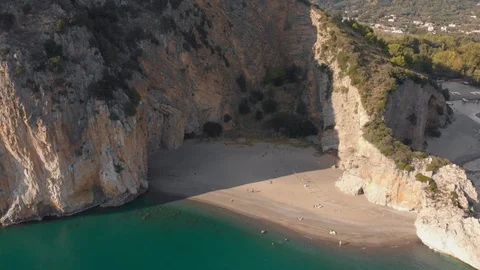 Sandy beach between steep rocks. Mediterranean coastline in sunny day. Aerial Stock Footage 99002268