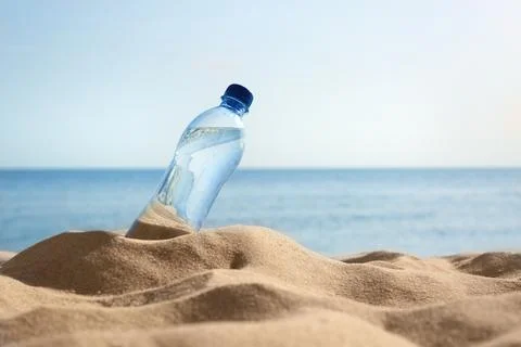 Sandy beach with bottle of refreshing drink on hot summer day, space for text Stock-Fotos