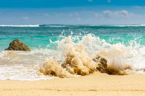 Sandy beach, breaking waves on the rocks. Indian ocean. Gradation of natural  Stock Photos