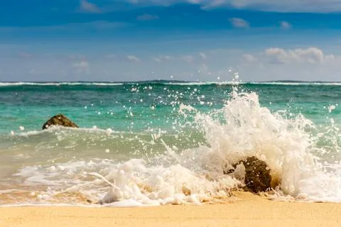 Sandy beach, breaking waves on the rocks. Indian ocean. Gradation of natural  Stock Photos