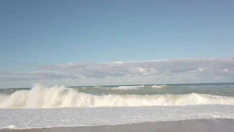 Sandy beach. Bright blue sky, white clouds. Windy. Large sea waves, white foam Stock Footage 144112469