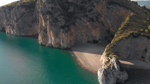 Sandy beach closed by rocky cliffs. Aerial shot of seaside natural arch of Stock Footage 102456438