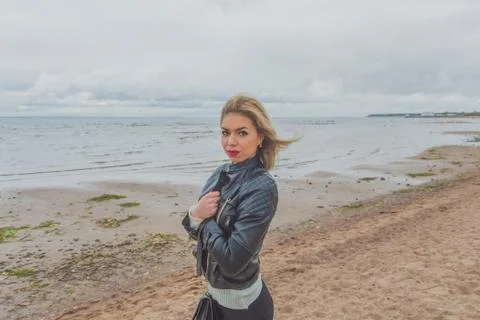 On a sandy beach on a cloudy day walking beautiful girl 库存照片