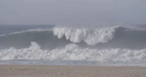 Sandy beach with dramatic ocean waves splashing in slow motion in Nazare 스톡 동영상 160783032