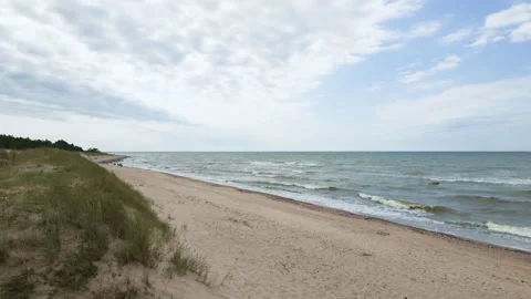 Sandy beach with dunes and sea waves under cloudy sky Stock Footage 346479510