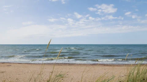 Sandy beach with dunes grass and sea waves on sunny day Stock Footage 345530336