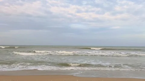 Sandy beach with gentle waves and clouds creating a peaceful natural scenery Stock Footage 319734332