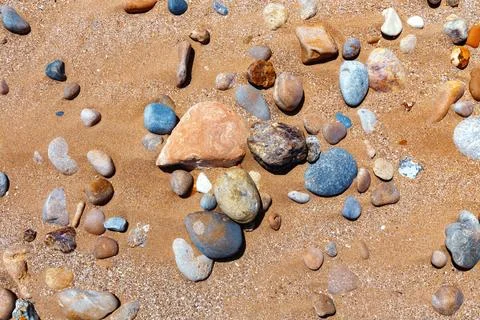 Sandy beach with the multicolor pebbles on the african Atlantic ocean coast. Stock Photos