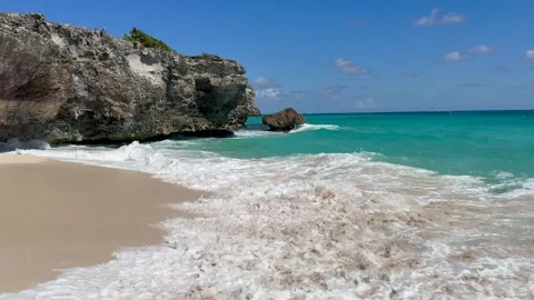 Sandy beach next to a rocky cliff, waves hitting the beach Stock Footage 321405664