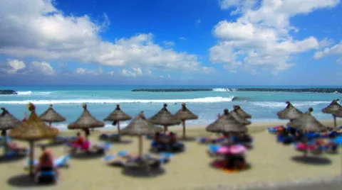 Sandy beach, ocean, thatched umbrellas &amp; blue sky - tilt shift time lapse Stock Footage 6531760