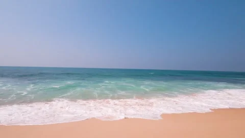 Sandy beach with ocean waves. Beautiful sunny day. Palm trees and buildings Vídeos de archivo 253478958