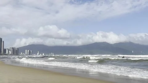 Sandy beach, ocean waves, palm trees, surfers in the distance, Da Nang, Vietnam Video stock 323928313