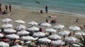 Sandy beach with parasols and sunbeds full of people sunbathing and swimming HD Footage
