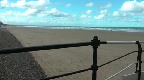 Sandy beach from pier with black and white railings  blue sky and bright clouds. Stock-Footage 12602867
