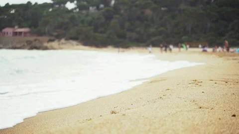 On the sandy beach in a pine bay. White foam waves. In the background, people Video stock 132967612