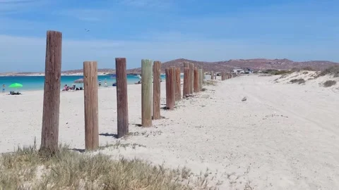 Sandy beach posts blue water desert dunes backdrop Stock Footage 172424658