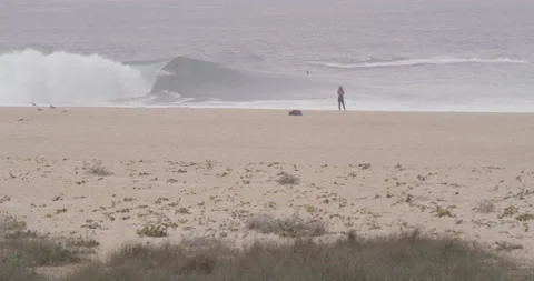 Sandy beach with pro surfers riding big waves on jet ski in ocean in slow motion Stock Footage 155607751