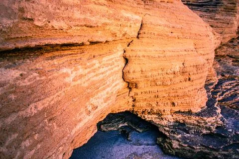 Sandy beach rocks colored in orange under the rays of the rising sun. Stock Photos