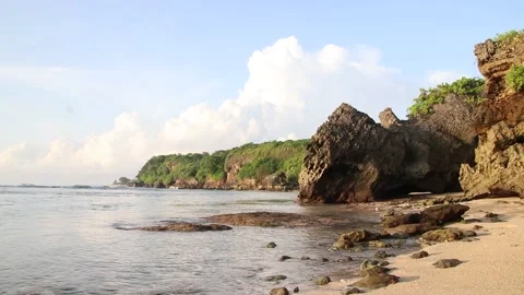 A sandy Beach with rocks, a serene and tropical ocean scenery in Bali Stock Footage 231017221