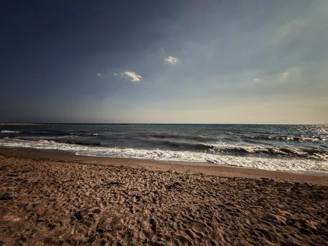Sandy beach with rolling waves under a dramatic open sky Фото