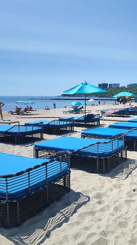 Sandy beach sea with empty blue sun loungers sunny hot summer day Vertical Stock Footage 327669772