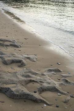 Sandy beach shoreline with an array of stones scattered along the coastline, Gre 库存照片