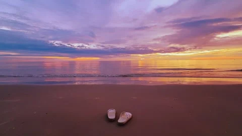 Sandy beach at sunset with two sandals and colorful sky over calm sea Vídeos de archivo 321288086