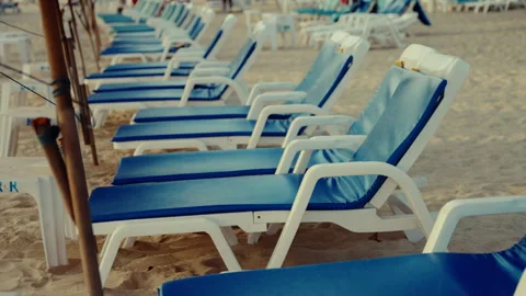 Sandy beach in thailand featuring neatly arranged blue and white lounge chairs Stock Footage 308513566