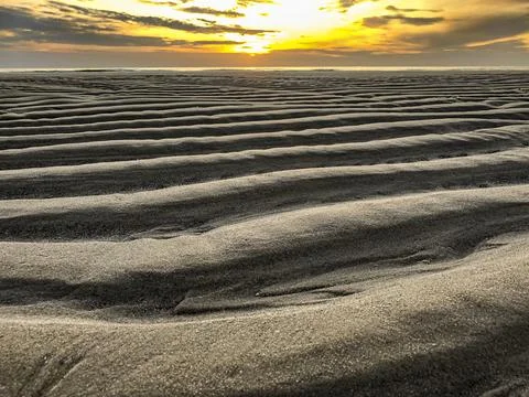 Sandy beach with wave pattern at sunse 스톡 사진