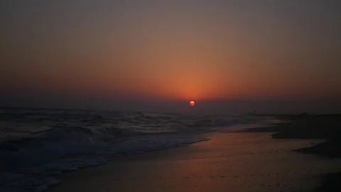 Sandy beach with waves and sea foam in the rays of the passing sun. HD Stock Footage 80231524