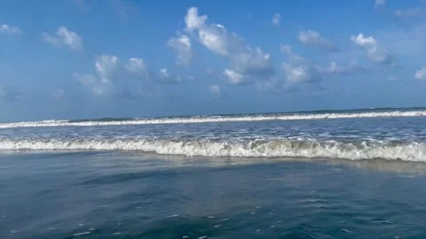 Sandy beach with waves crashing against the shore under a clear blue sky. Stock Footage 334163295