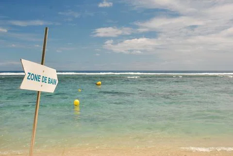 Sandy beach with a "Zone de Bain" sign in French 库存照片