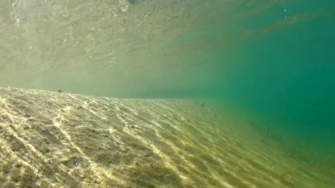Sandy bottom of shallow lake in sunlight. Underwater shooting. Stock Footage 243429633