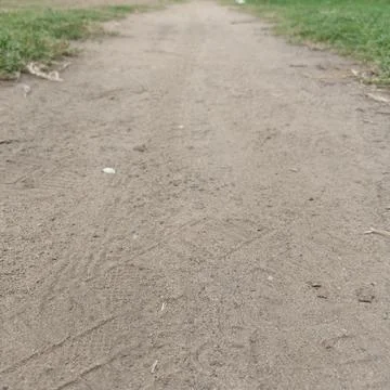 Sandy dirt walking trail path going forward grassy green park sun Stock Photos
