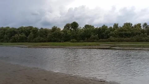 A sandy, gently sloping bank of a small channel bordered by a strip of fore.. Stock Photos
