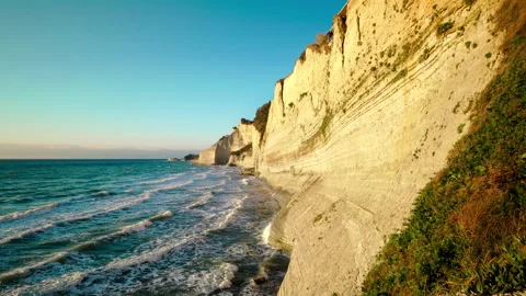Sandy high cliff and coast by Mediterranean sea with waves and wind at sunset Stock Footage 279644119