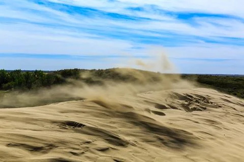 A sandy hillside with a cloud of dust in the air Stock Photos