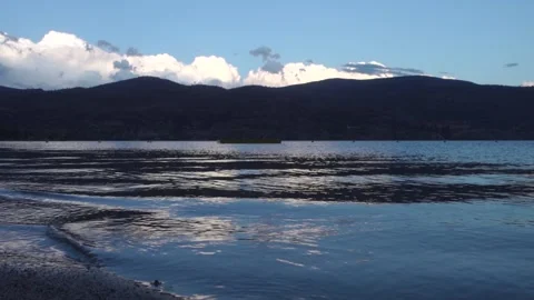 Sandy Lake Shore with Small Waves Lapping and Cloudy Mountains Stock Footage 232050194