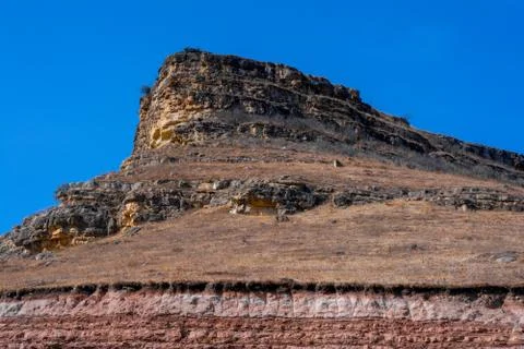Sandy mountain with a sharp cliff and a small amount of vegetation against th Stock Photos