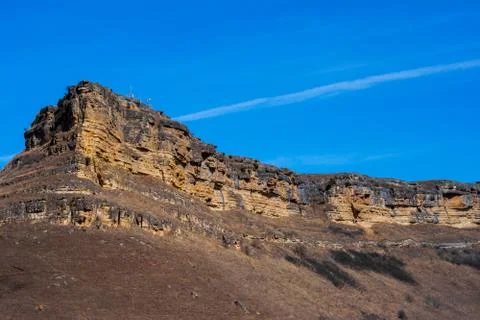 Sandy mountain with a sharp cliff and a small amount of vegetation against th Stock Photos