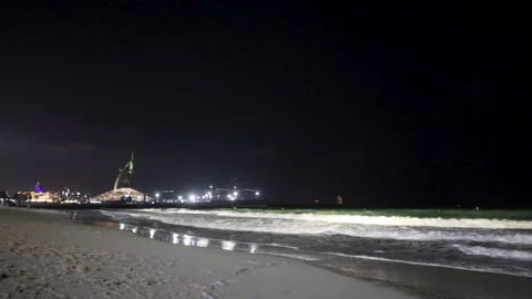 Sandy Night beach in Dubai with Burj Al Arab on a windy evening Stock Footage 301588256