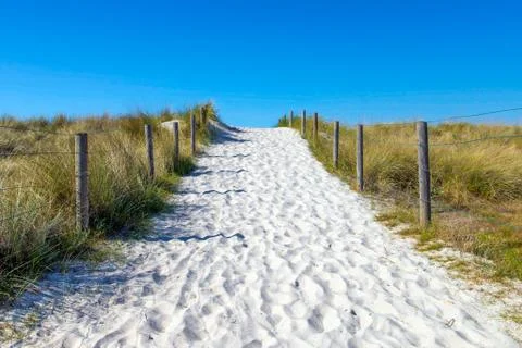 Sandy path between green grass against a blue sky Stock-Fotos