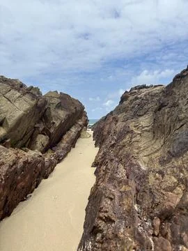 Sandy path between large rock formations on a beach in Malaysia Stock Photos