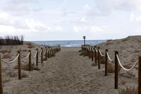 Sandy path leading to ocean through protective dunes Stock Photos