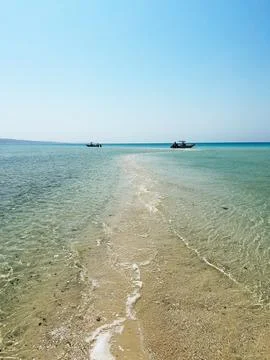 Sandy pathway leading into clear blue ocean Stock Photos