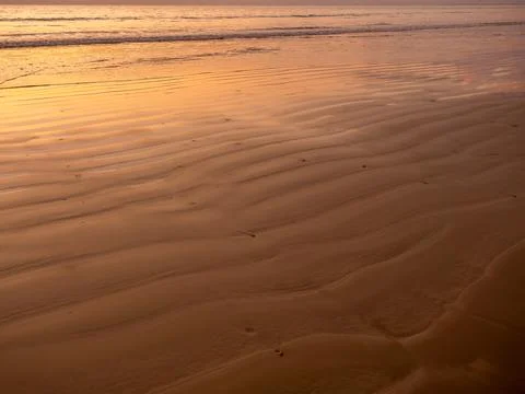 Sandy pattern and curved texture on the beach created by waves and sea bree.. Stock Photos