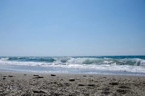 The sandy-pebble beach with waves and a clear horizon on a Sunny day Stockfoto's