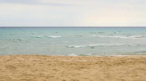 Sandy sea shore in cloudy weather and waves lapping on the beach and form a Stock Footage