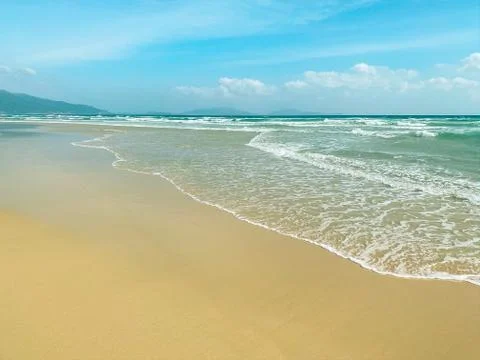 Sandy seashore, calm soft waves at sea, sunny weather, blue sky with white cl Stock Photos