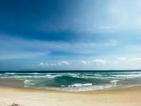Sandy seashore, calm soft waves at sea, sunny weather, blue sky with white cl Stock Photos